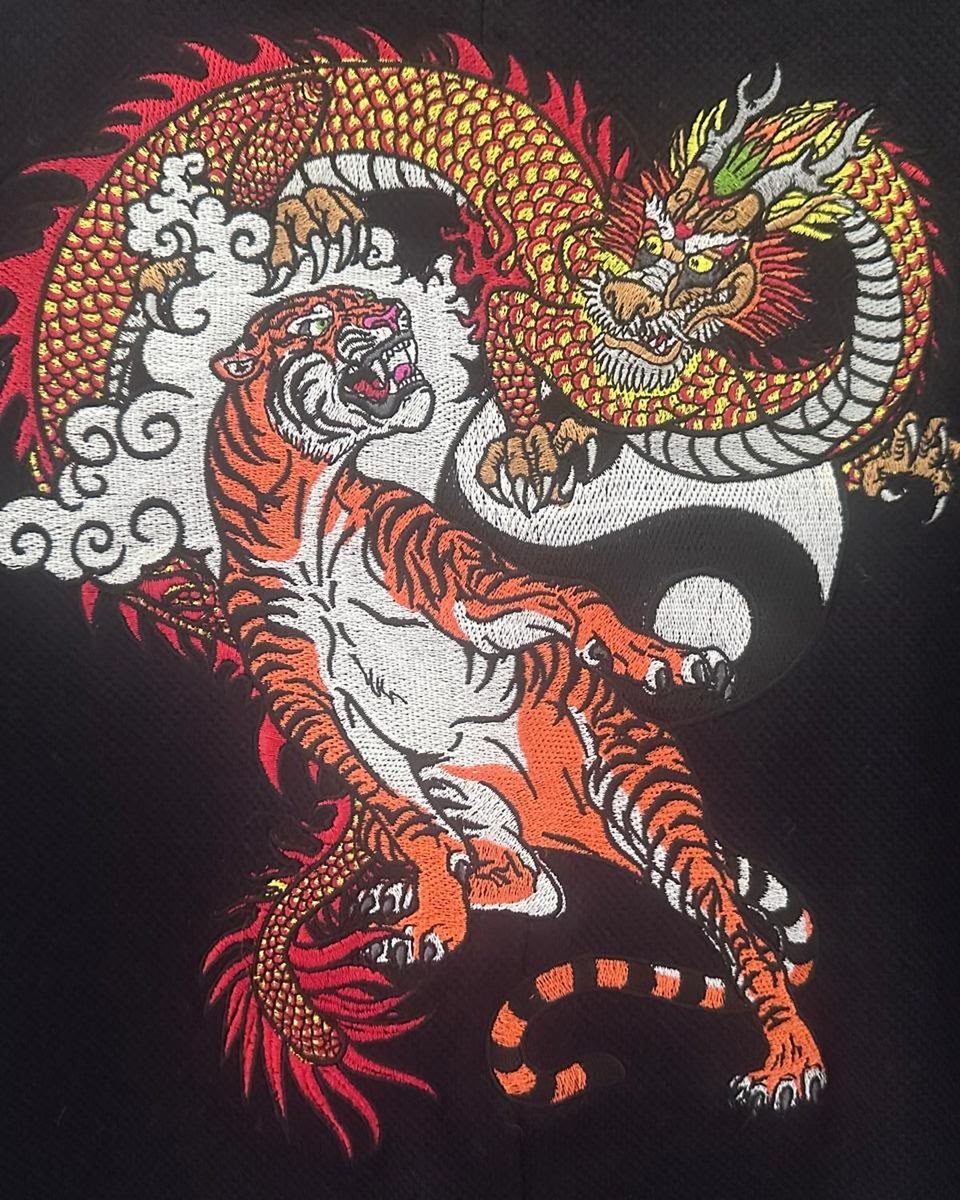Broderie multicolore d'un dragon et d'un tigre sur polo piqué noir